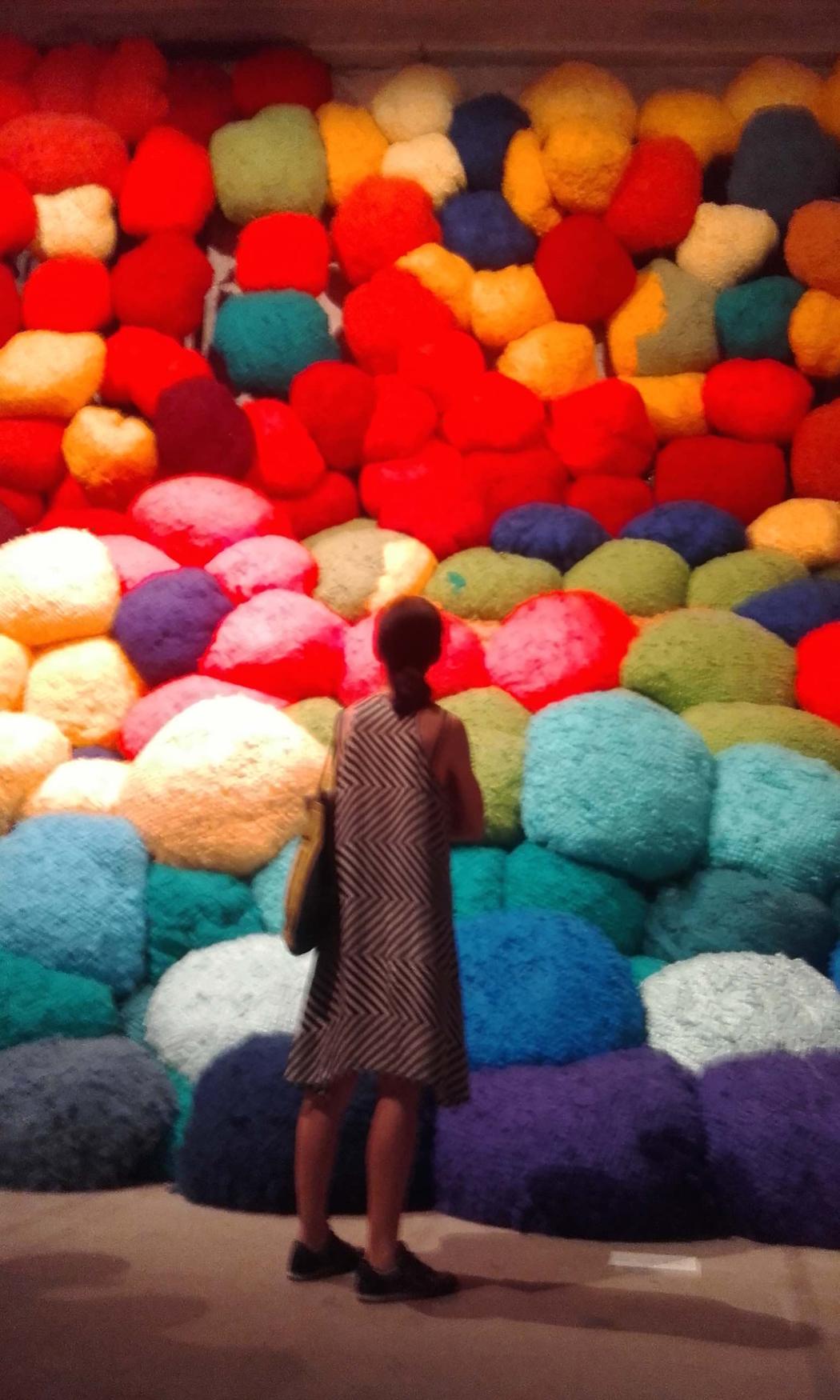 A woman standing in front of a pile of colourful puffy balls.